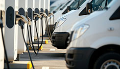 Eine Fahrzeugflotte von Lieferwagen lädt gerade an mehreren Ladesäulen.